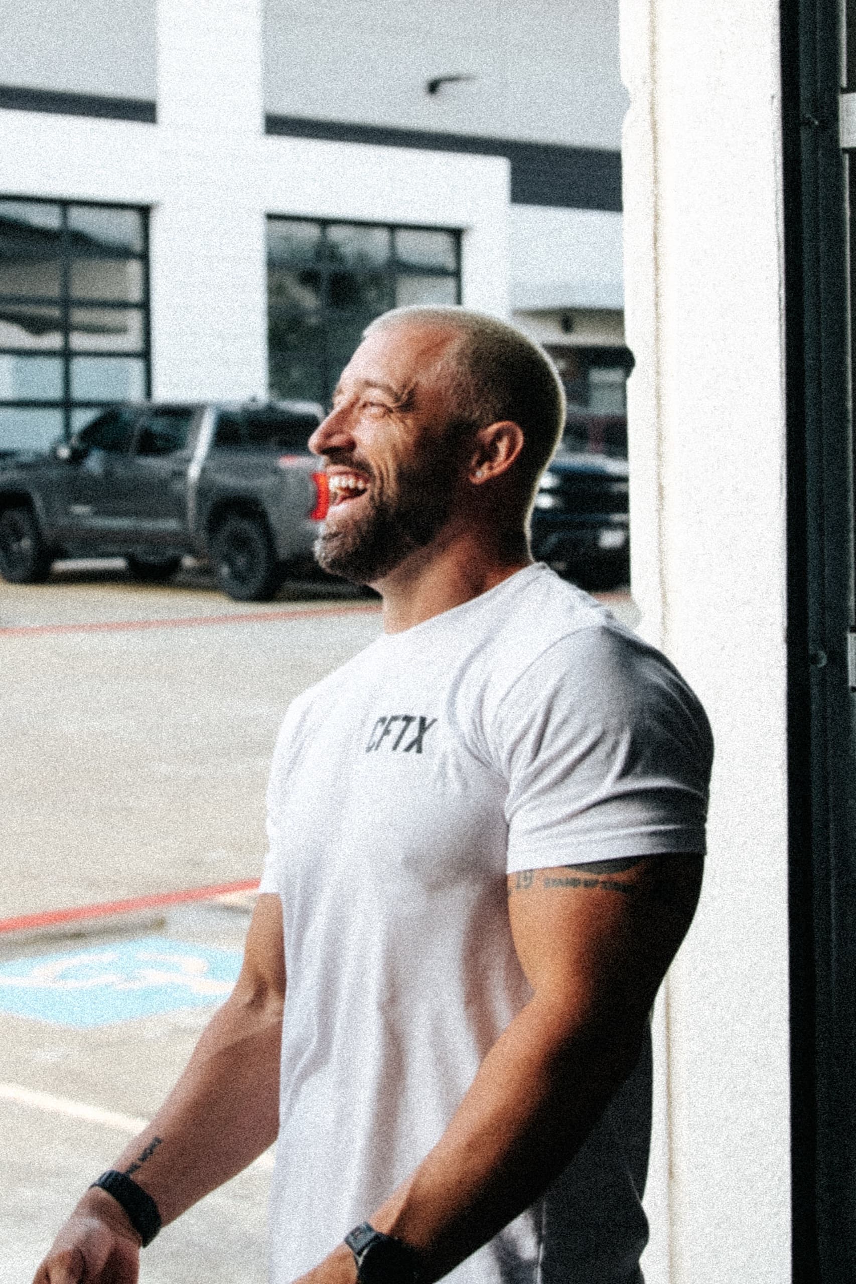 A CrossFit Texas coach laughing outside the gym in a CFTX tee