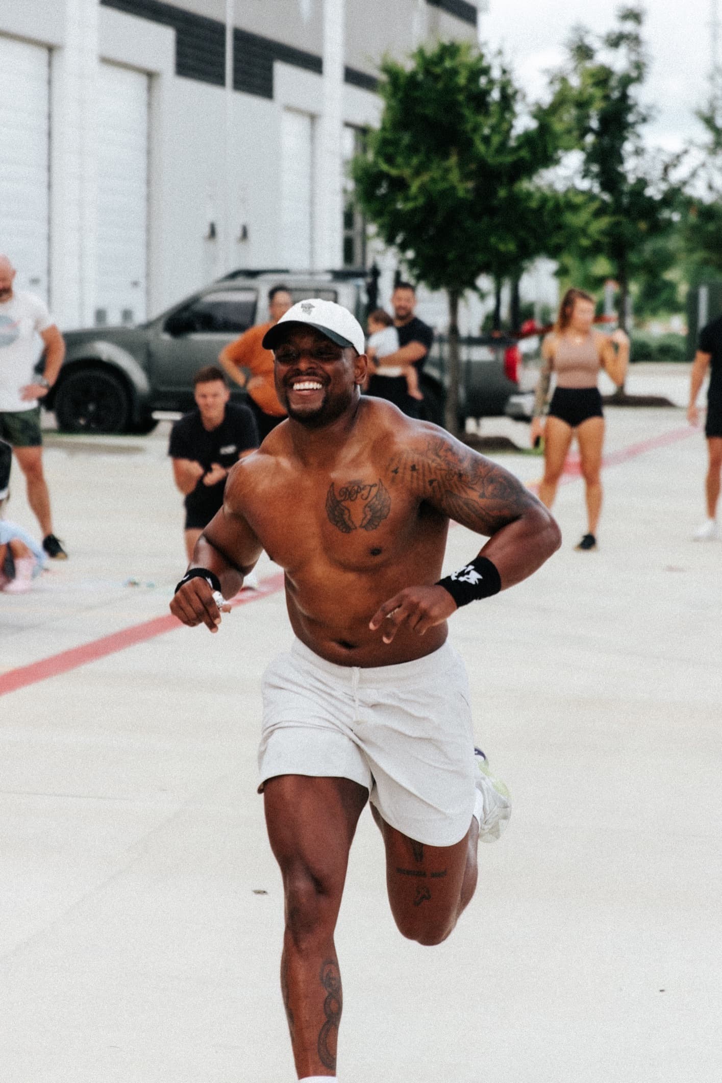 A smiling CrossFit Texas athlete sprinting a conditioning piece on the pavement outside the gym while the class looks on